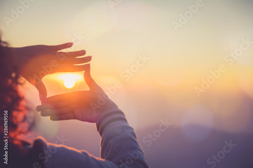 Fototapeta The woman making frame round the sun with her hands in sunrise,Future planning idea concept