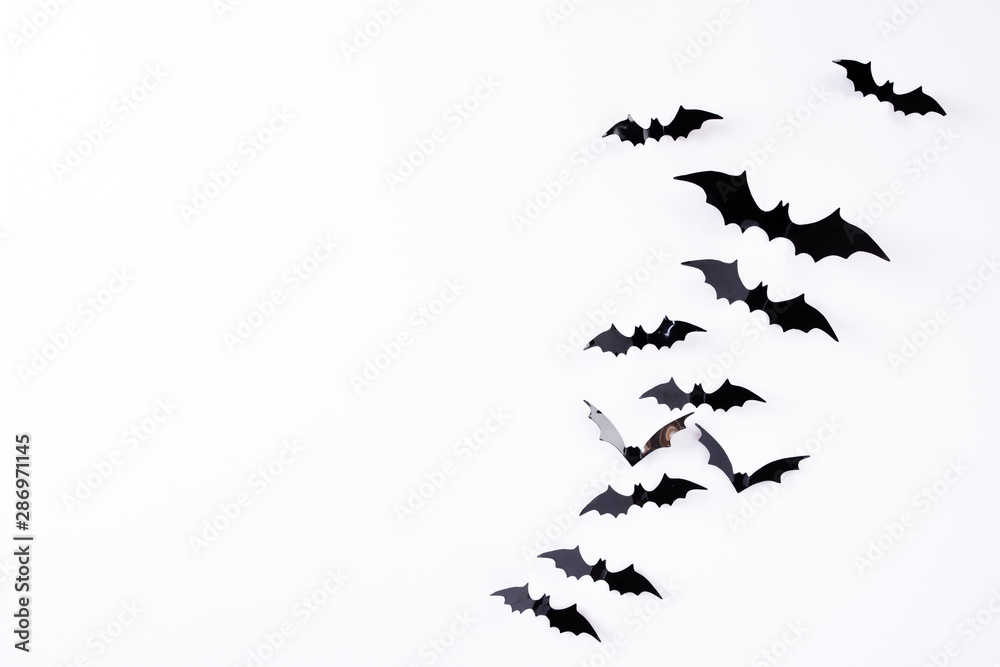Top view of Halloween crafts, black paper bats flying over white background with copy space for text. halloween concept.