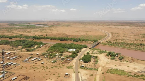 Retreating aerial footage of Omorate town and bridge crossing the Omo river, near the border between Ethiopia and Kenya photo