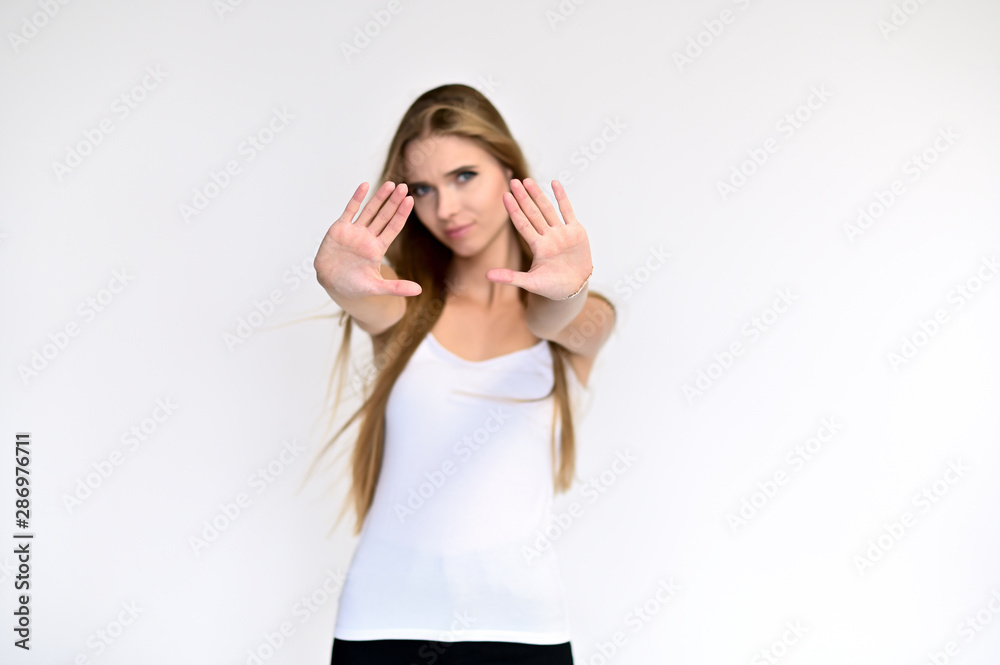 Portrait of a beautiful pretty girl student in a white T-shirt with long curly hair on a white background. Beauty and brightness. Shows hands to the side, smiles with different emotions. Portrait of a beautiful pretty girl student in a white T-shirt with long curly hair on a white background. Beauty and brightness. Shows hands to the side, smiles with different emotions.