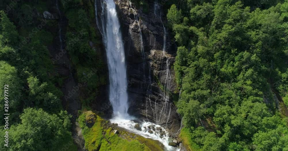 Aerial: Drone shot of beautiful waterfall on cliff amidst trees in forest - Geiranger Fjord, Norway Aerial: Drone shot of beautiful waterfall on cliff amidst trees in forest - Geiranger Fjord, Norway