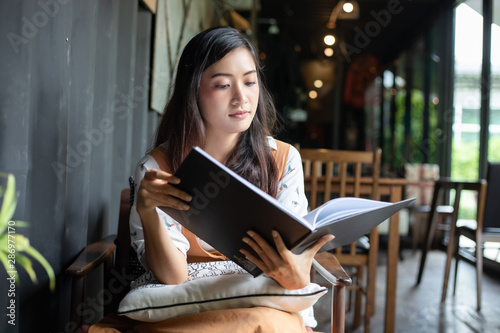 Asian women reading and smiling and happy Relaxing in a coffee shop after working in a successful office.