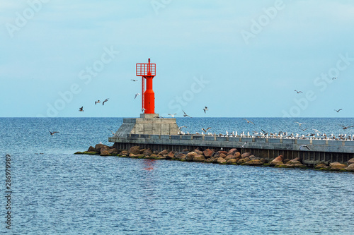 Red lighthouse on a breakwater in Baltic sea, the Pavilosta, Latvia