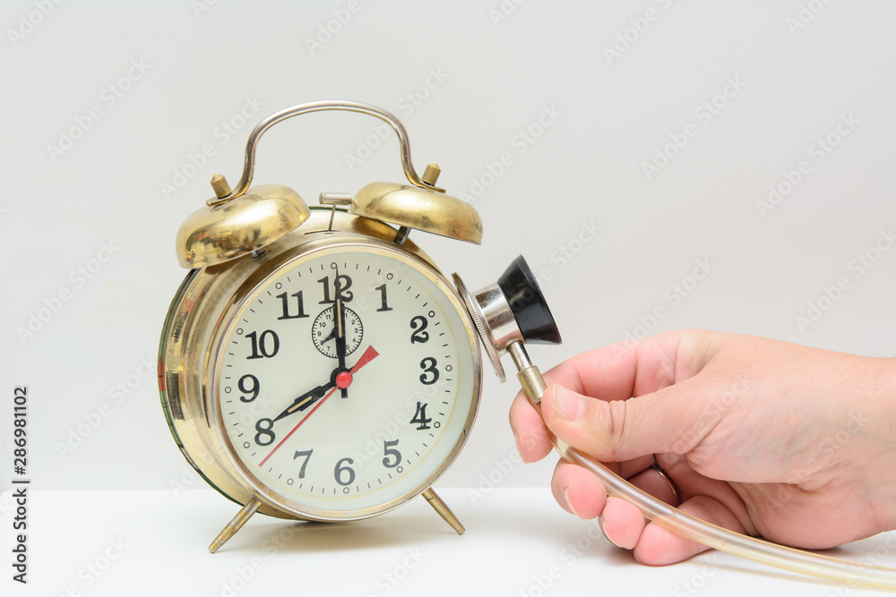 n the hands of men a stethoscope. The doctor pressed a stethoscope to the surface of the alarm clock. Concept - heart disease. Spoiled time. Listen to the heart, time. n the hands of men a stethoscope. The doctor pressed a stethoscope to the surface of the alarm clock. Concept - heart disease. Spoiled time. Listen to the heart, time.