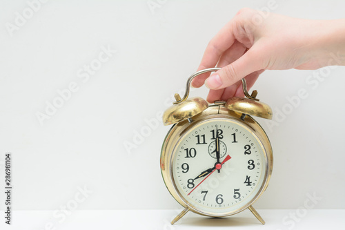 Female hand holds a vintage alarm clock. The concept is to wake up to work. Time to work