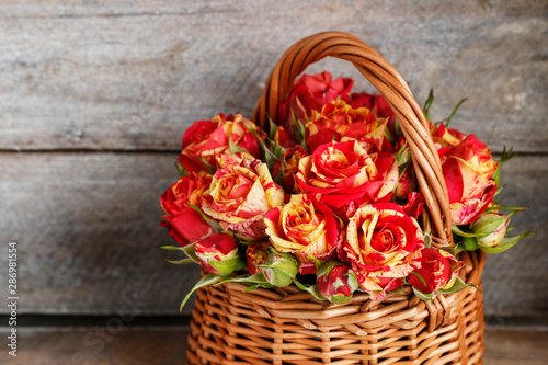 Roses in wicker basket on wooden background. Postcard motif.