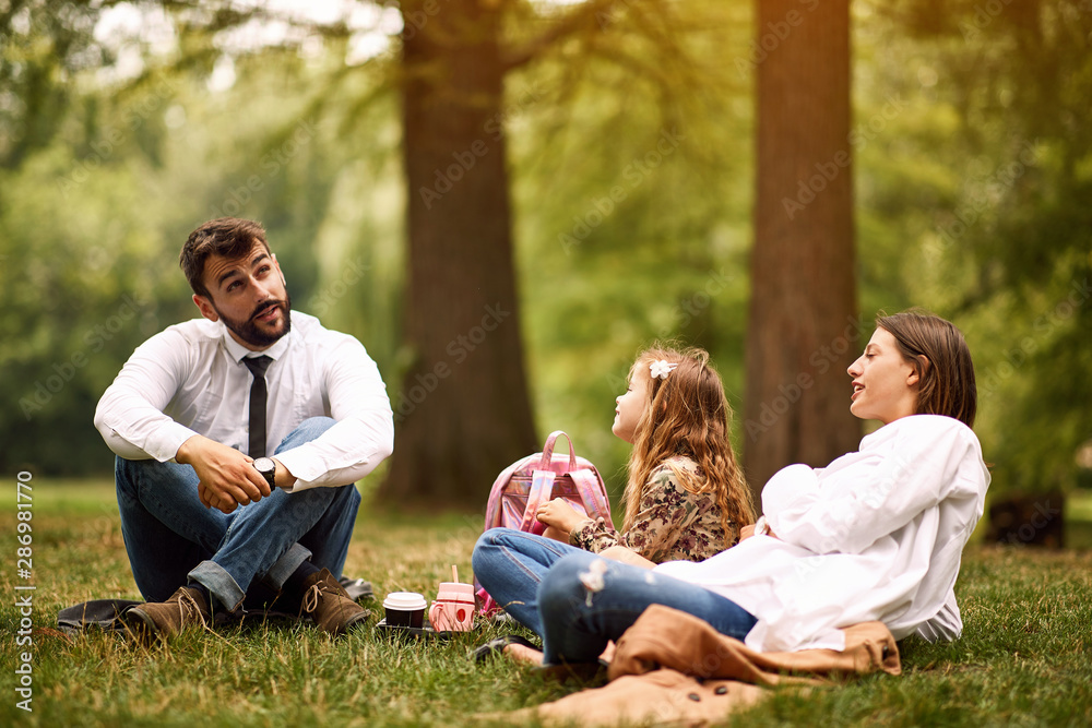 Mother and father with their daughter after work and school sitting and resting at park.. Mother and father with their daughter after work and school sitting and resting at park..