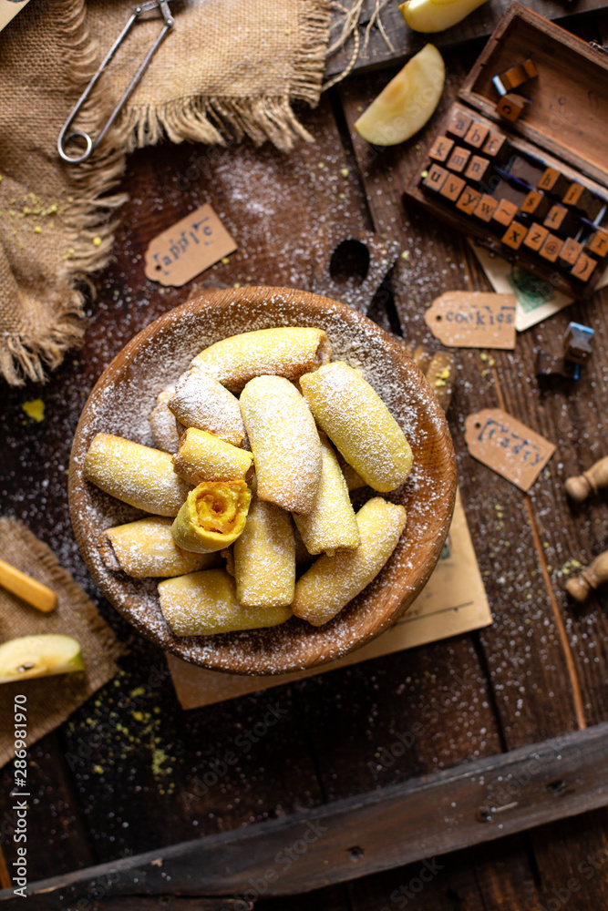 Fototapeta premium homemade shortbread yellow baked rolled cookies or bagels with apple jam in wooden round plate