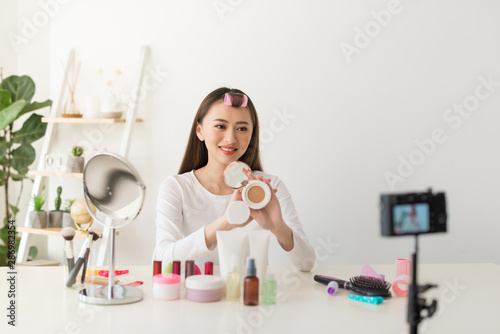 Young woman professional beauty vlogger or blogger recording cosmetic makeup tutorial with camera to share on social media