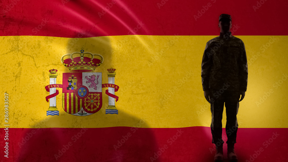 Fototapeta premium Spanish soldier silhouette standing against national flag, proud army sergeant