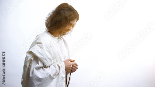 Saint man praying with Rosary, light falling as sign of forgiveness, salvation