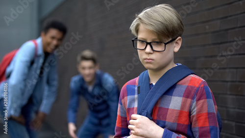 Bild auf Leinwand Evil teen boys laughing at new student in school, calling names, verbal bullying
