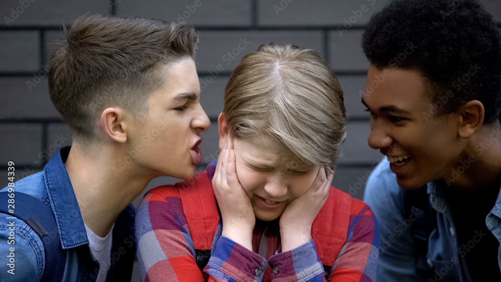 Aggressive high school students teasing boy calling names, face-to-face bullying Aggressive high school students teasing boy calling names, face-to-face bullying
