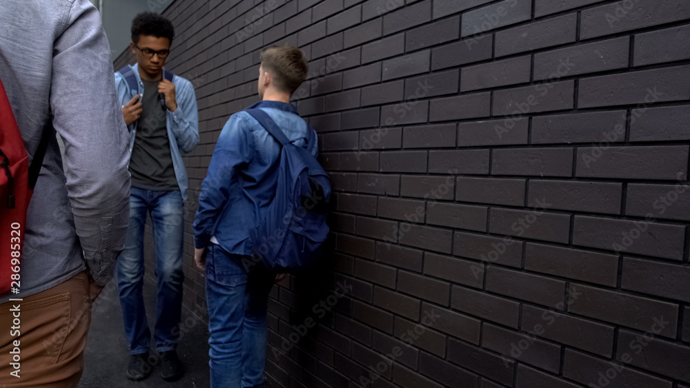 Schoolboys threatening weak afro-american student in backyard, racial bullying Schoolboys threatening weak afro-american student in backyard, racial bullying
