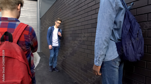 Canvas Print Hooligans threatening weak boy in school backyard, bullying, provoking conflict