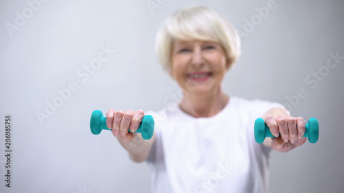 Active senior lady lifting dumbbell, exercises for health support, lifestyle