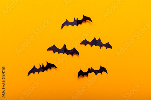 Crafts for the concept celebration of Halloween. Figures of a black bat, cut from black paper on yellow background. Place for text Mock up Top view
