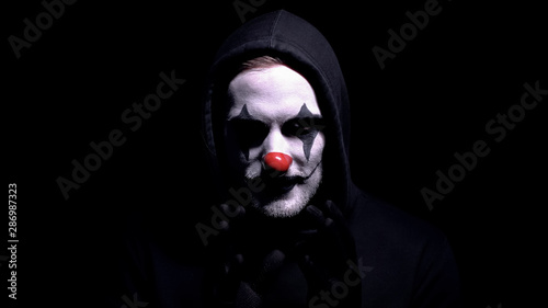 Crazy man in spooky clown mask staring at camera, murder or robbery threat