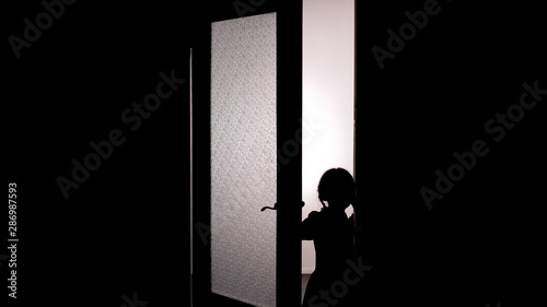 Bild auf Leinwand Little female child silhouette opening door into darkness, horror scene, mystic