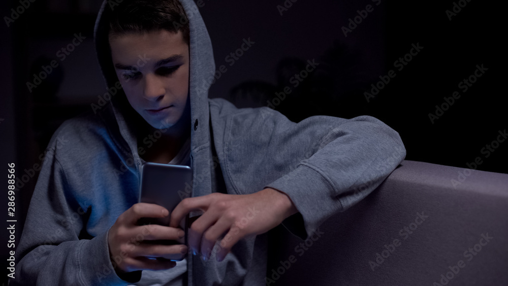 Teen boy playing smartphone late at night instead of sleeping, lack of control Teen boy playing smartphone late at night instead of sleeping, lack of control
