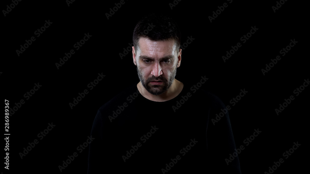 Worried sweaty male looking down dark background, problem hopelessness, crisis Worried sweaty male looking down dark background, problem hopelessness, crisis