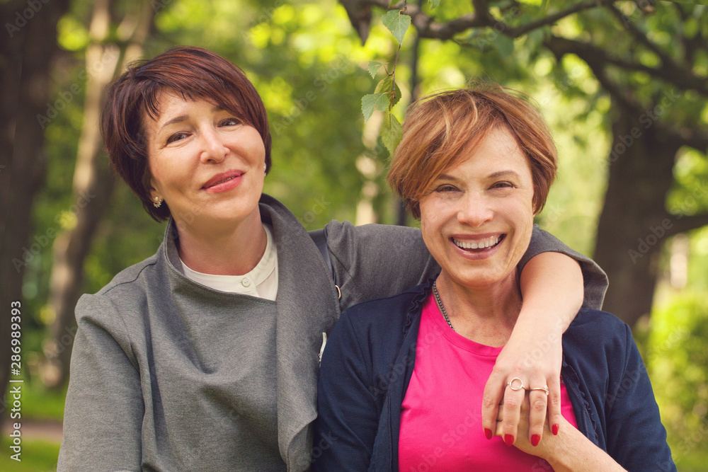 Two happy women walking in summer park, portrait Two happy women walking in summer park, portrait