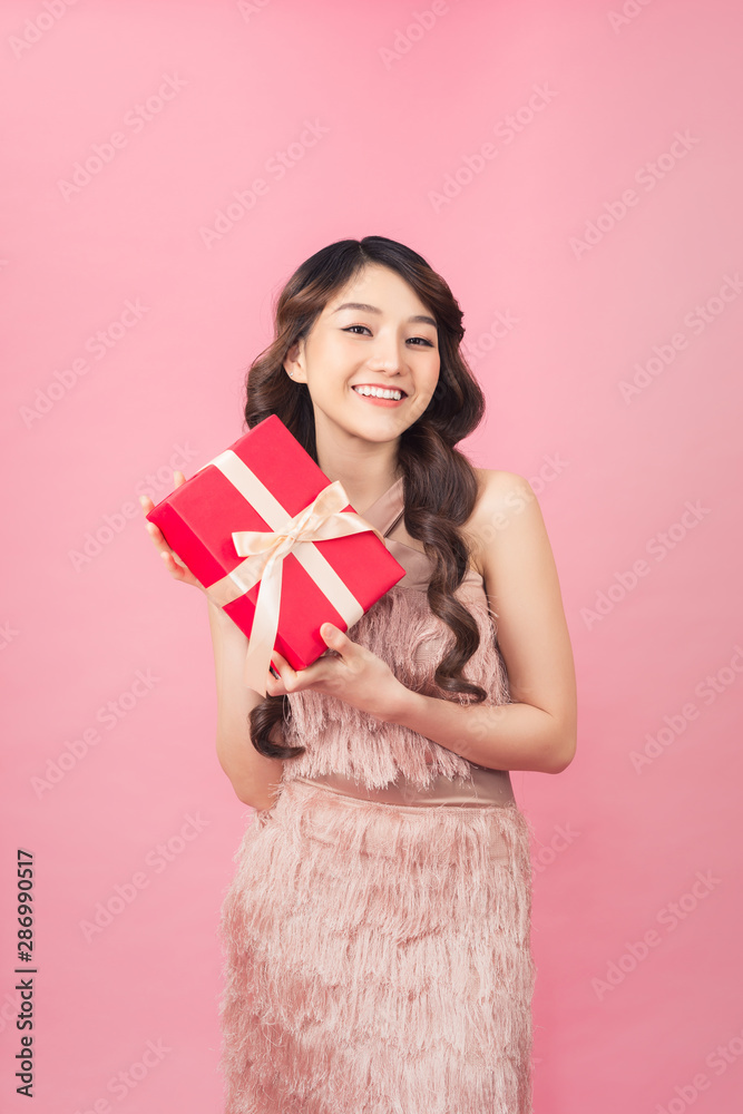Young woman holding gift box with biege bow being excited and surprised holiday present Young woman holding gift box with biege bow being excited and surprised holiday present