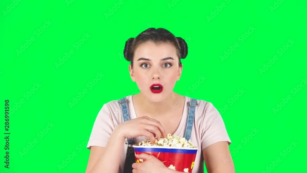 Sweet girl chews popcorn while watching a movie. Girl watching with spellbound, slow motion Sweet girl chews popcorn while watching a movie. Girl watching with spellbound, slow motion