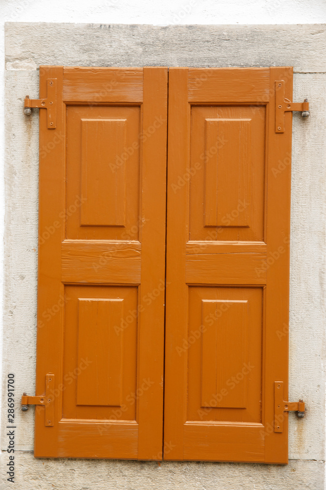 Closed brown rustic wooden window on stone wall.