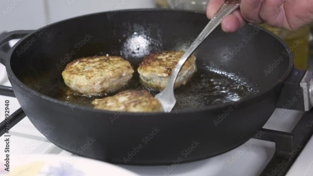Woman making pan fried chicken cutlets in cast iron frying skillet with oil on gas stove. Woman making pan fried chicken cutlets in cast iron frying skillet with oil on gas stove.