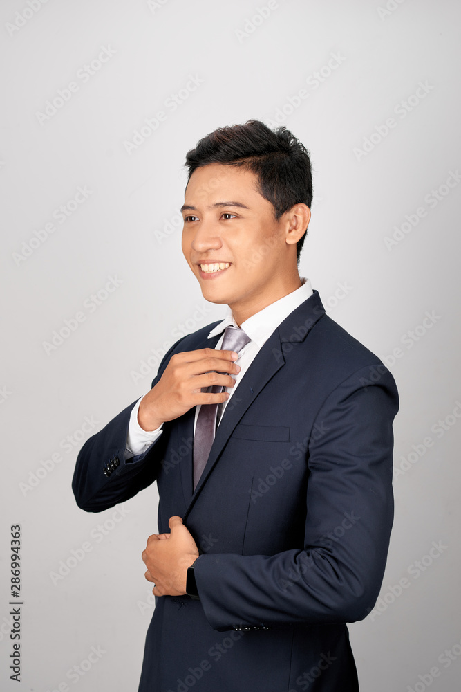 Asian Businessman adjusting gray tie, isolated on white background Asian Businessman adjusting gray tie, isolated on white background