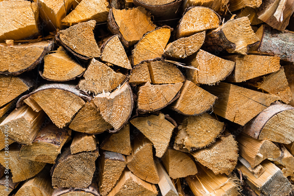 A firewood stacked in a pile, cut trunks. Close up shot, wood background. A firewood stacked in a pile, cut trunks. Close up shot, wood background.