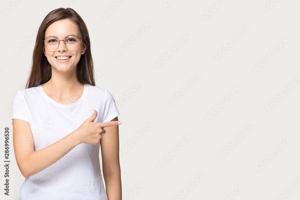 Smiling millennial girl in glasses point at blank copy space Smiling millennial girl in glasses point at blank copy space