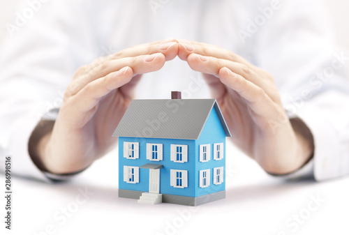 Small blue house covered by hands 