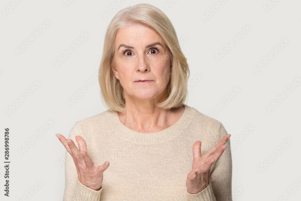 Surprised aged woman isolated on grey background shocked by deal Surprised aged woman isolated on grey background shocked by deal