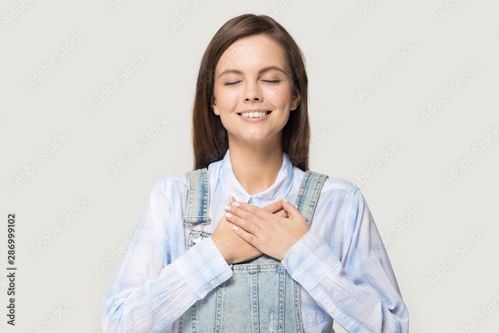 Grateful millennial girl with hands at chest show appreciation Grateful millennial girl with hands at chest show appreciation