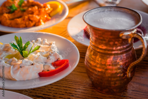 traditional turkish appetizers on table in evening sun light and ayran in a copper glass