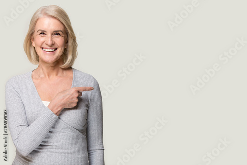 Smiling aged woman point at blank copy space