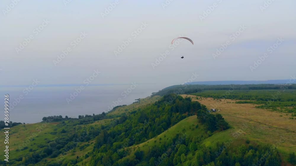 Green slopes and the parawing flying above them Green slopes and the parawing flying above them