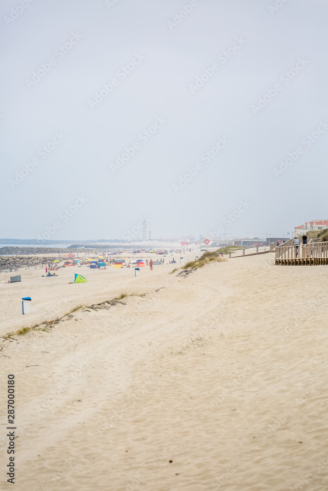 View of pedestrian wooden path on beach, people walking and people taking sunbath on beach View of pedestrian wooden path on beach, people walking and people taking sunbath on beach