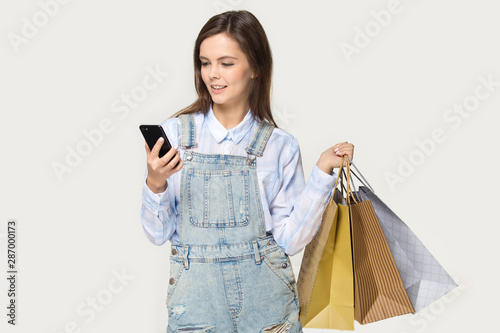 Teenage girl hold shopping bags buying online using smartphone