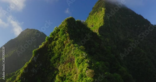 Aerial drone shot pushing in on lush green island mountain peaks, flying over green mountain ridges, gorgeous island landscape