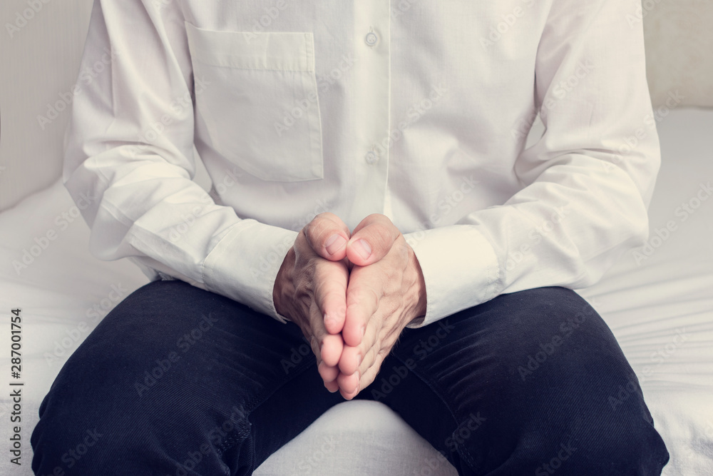Obraz premium Man sitting on the bed and quietly waiting for someone, man's hands, cropped image, close-up, toned
