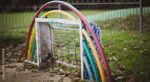 An abandoned painted childrens football goal in a playground with peeling paint