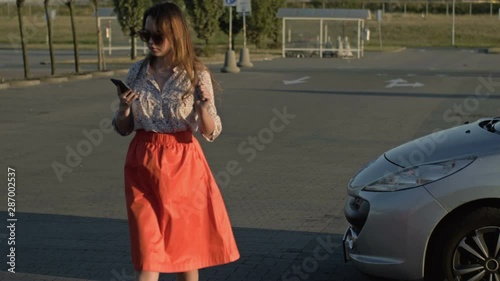 Beautiful caucasian girl walking down the street looking at her cell phone was almost hit by a car. Concept - smartphone addiction.