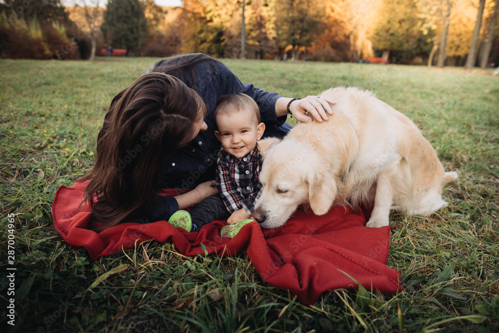 Mother,babyboy and a golden retriever in a beautiful autumn park Mother,babyboy and a golden retriever in a beautiful autumn park