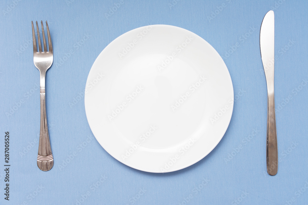 Cutlery set with plate. Dish, fork and knife, copy space, blue background, closeup, top view Cutlery set with plate. Dish, fork and knife, copy space, blue background, closeup, top view
