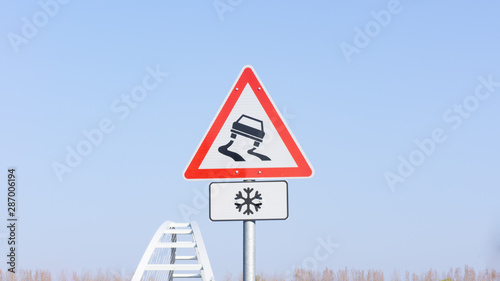 Traffic sign warns about slippery road ahead