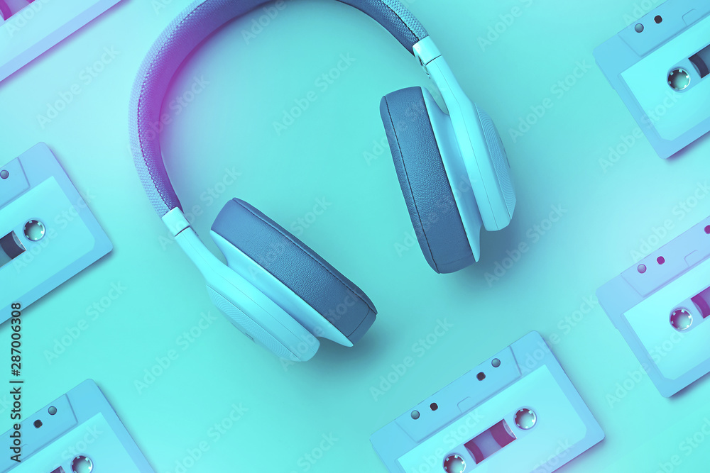 Turquoise headphones with audio cassette on a colored background. Music concept. Pattern of audio cassettes. Colored headphones isolated