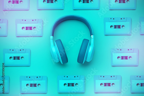 Turquoise headphones with audio cassette on a colored background. Music concept. Pattern of audio cassettes. Colored headphones isolated